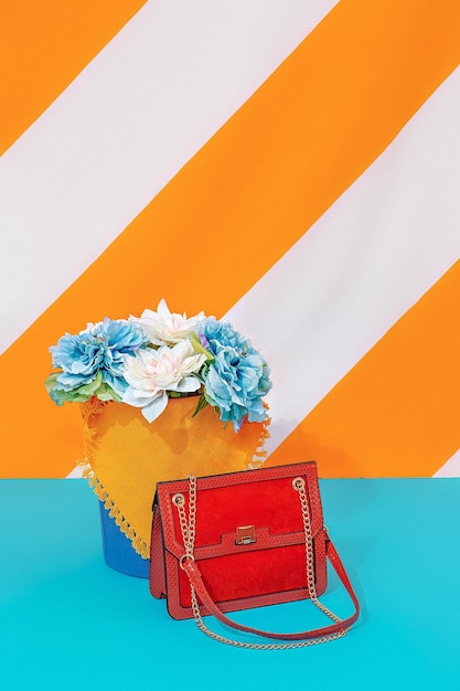 Flowers arrangement and bag on bright striped yellow background. Spring summer minimal concept. Still life fashion