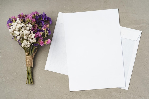 Flowers, blank paper and envelope on a table top view