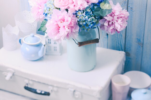 Цветы в синей винтажной банке на белой ретро-сумке и кухонной посуде