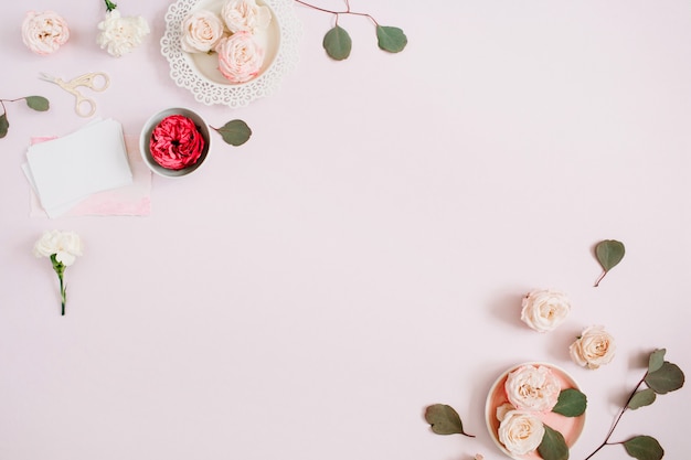 Flowers border frame made of beige and red roses and white carnation on pale pastel pink