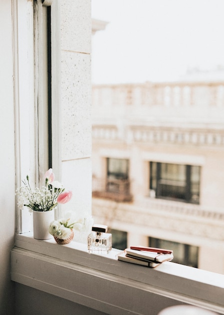 Photo flowers by a perfume bottle on a windowsill