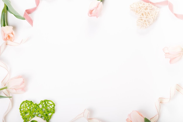 白い背景のバレンタインデー フラット レイアウト トップ ビューにピンクの花で作られた花の組成フレーム