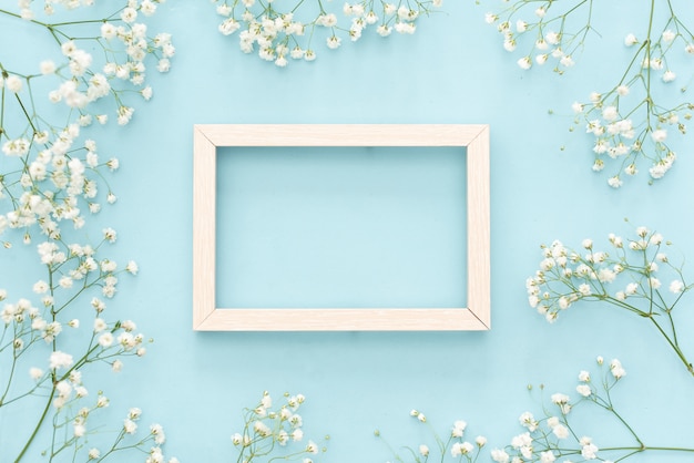 Flowers composition romantic. White gypsophila flowers, photo frame on pastel blue background