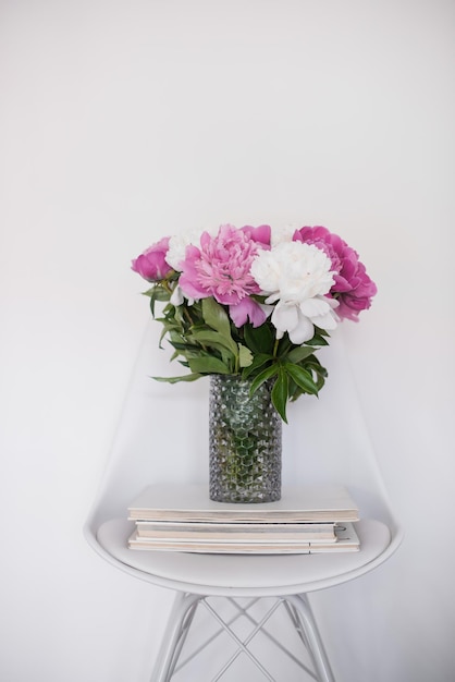 Flowers decor fresh peonies on designer chair in white room int