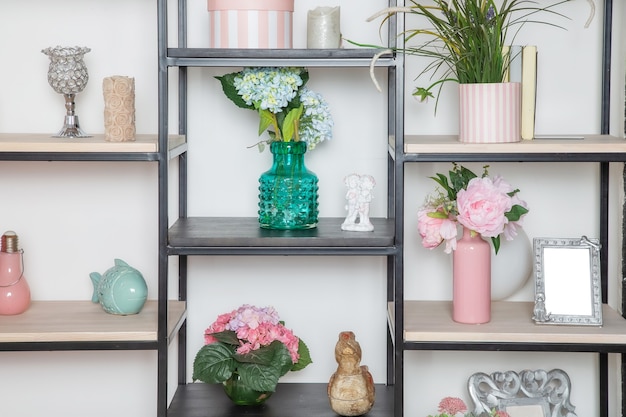 Photo flowers and decorative decorations on a metal rack in the style of minimalism in the living room in a scandinavian style