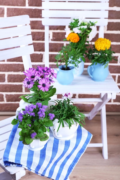 Flowers in decorative pots on table on bricks background