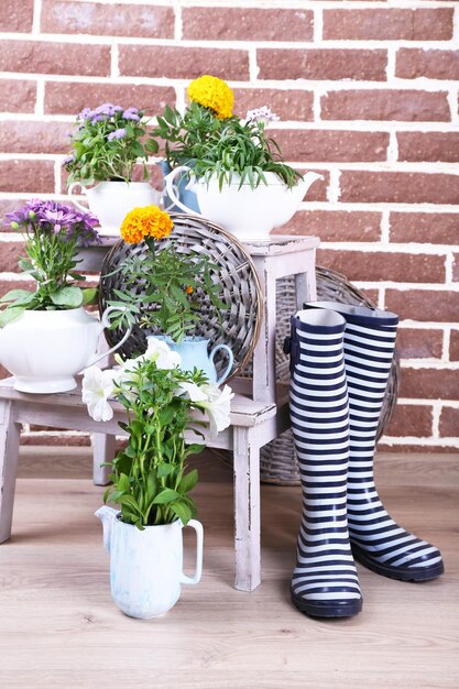 Flowers in decorative pots on wooden ladder on bricks background