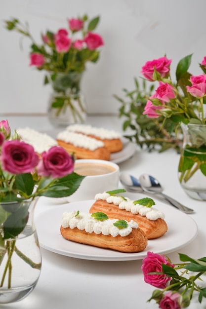 Fiori e bignè decorati con crema e menta su un tavolo bianco. dessert per un appuntamento romantico. torte per le feste.