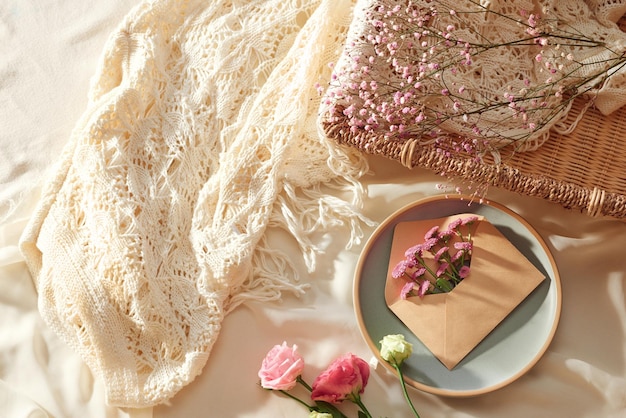 Flowers in envelope and fresh flowers with glasses and cup of tea on fabric background