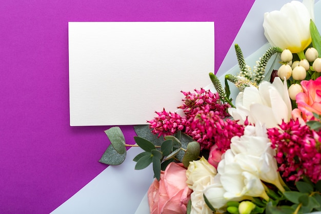 Flowers gift card. Congratulations card in bouquet of roses, tulips, eucalyptus on purple background.