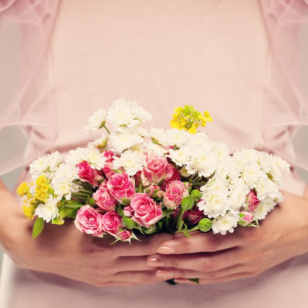 女性の手に花の贈り物。ピンクの花の背景