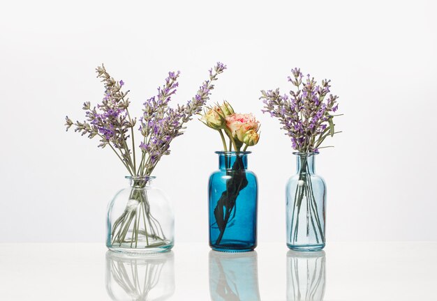 Flowers and herbs in glass bottles. Abstract flower bouquets in bottles isolated on white.