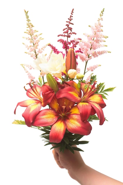 Flowers of lily, ixia and astilbe in a bouquet hold in hand isolated on white background. Flat lay, top view