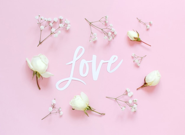 Flowers and  LOVE lettering on a light pink background top view