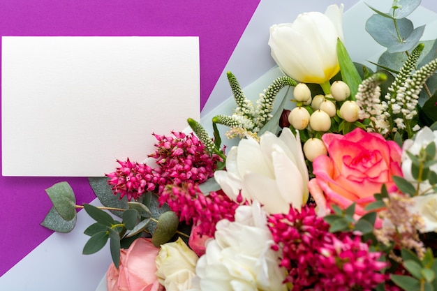 Flowers mock up gift card. Congratulations card in bouquet of spring flowers on purple background.