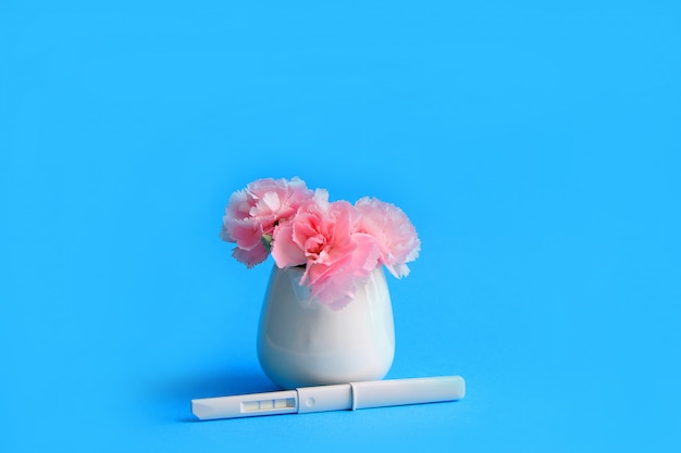 flowers and pregnancy test on a blue background