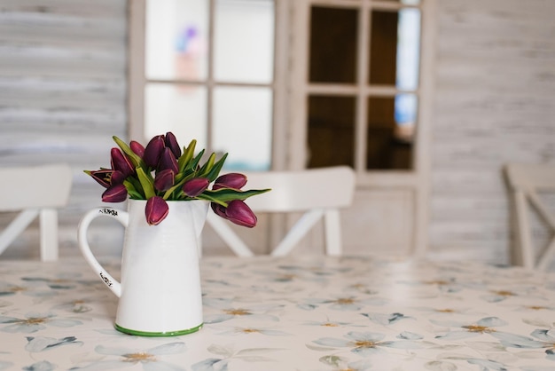 Flowers red tulips in a vase in the style of Provence are on the table in the kitchen Copy space