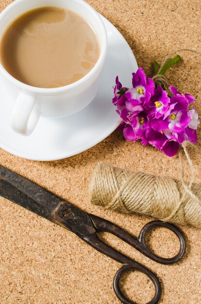 一杯のコーヒーの横にある花、はさみそしてジュート。