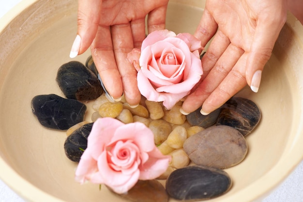 Photo flowers skincare and hands of woman in water bowl for cleaning or hygiene floral therapy spa treatment and female soak hand and washing with pink roses and stones for detox beauty and manicure