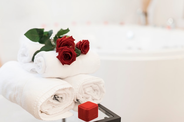 Flowers, towels and jewelry box near spa tub