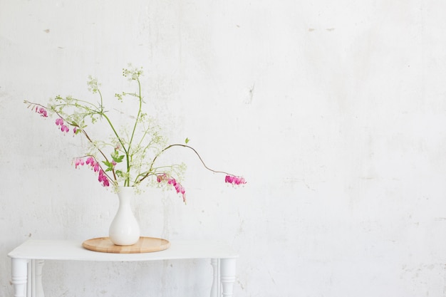 Flowers in vase on background white wall