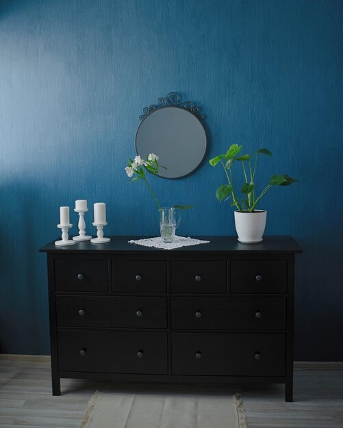 Flowers in a vase on a black dresser, mirror