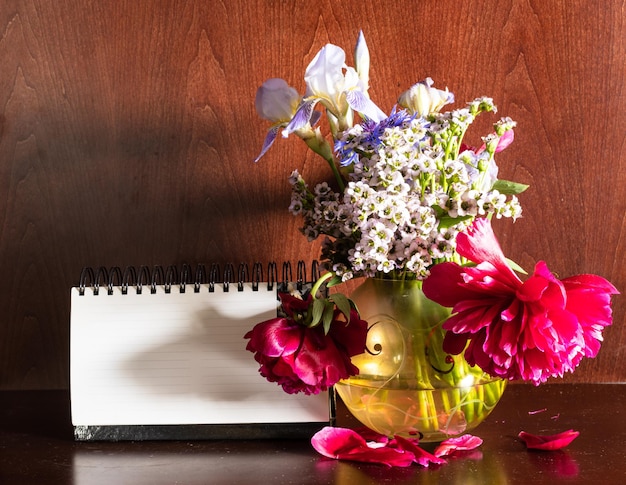 Flowers in vase and blank calendar on dark brown