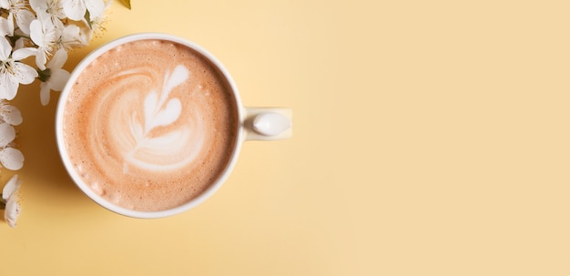 Flowers with mug cappuccino and heart decoration on foam on color surface