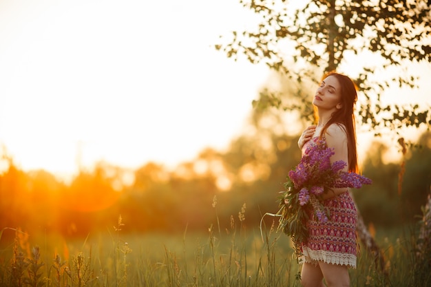 花とフィールドの女性の手のひら。点灯している夕方の太陽