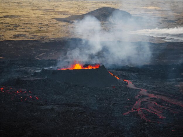 Flowing lava hot magma spilling out of the volcano crater aerial side view