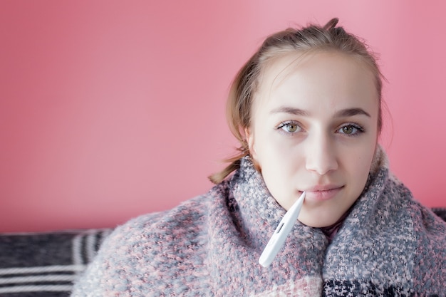 Flu cold grippe. Woman having high temperature. Sick girl with fever checking mercury thermometer on pink .