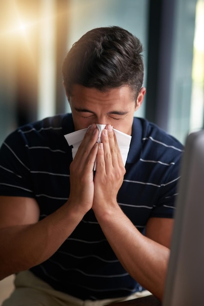 The flu germs have come Shot of a young businessman blowing his nose in an office