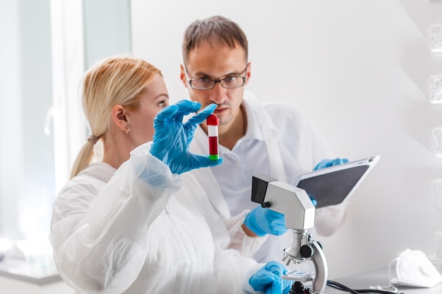 Flu virus experiment - scientist in laboratory with microscope, wear protective eyewear