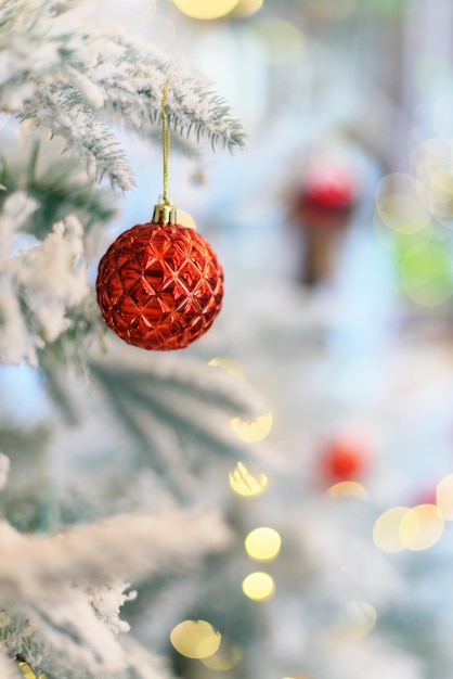 Foto soffici albero di natale smerigliato innevato artificiale decorato con palline rosse luminose e luci fatate. addobbi natalizi vintage