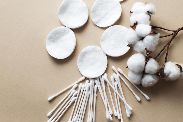 Foto soffici batuffoli di cotone con fiori di cotone e tamponi di cotone su sfondo beige