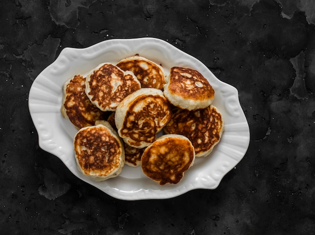 Fluffy fritters on kefir on a dark background top view