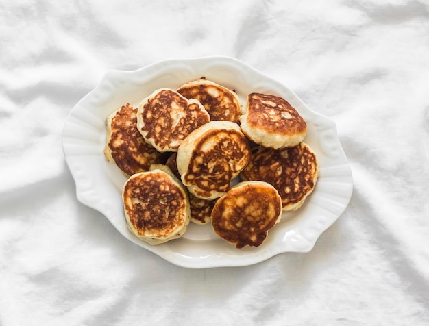 Fluffy fritters on kefir on a light background top view