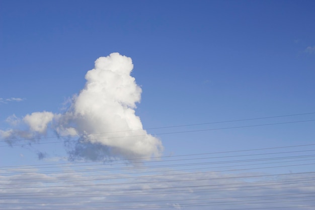 fluffy white cloud in blue sky with wires