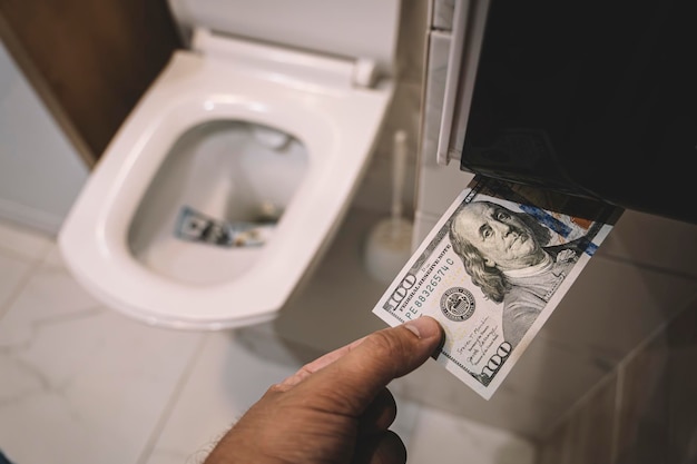 Flush money down toilet throws dollar bills in the toilet loss concept close up selective focus concept of senseless waste of money loss useless waste large water costs