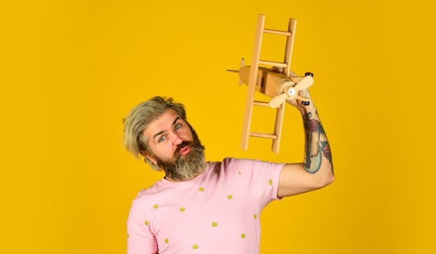 Fly on airplane Book tickets summer vacation Play with plane Cabin crew This is just beginning Private plane Air travel Transportation concept Aviator bearded hipster man Wooden plane toy