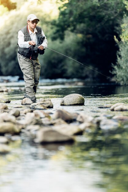 Fly fisherman using flyfishing rod in beautiful river.