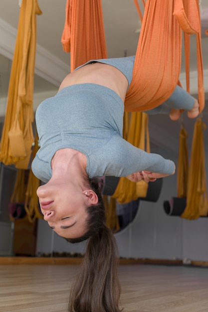 Fly yoga close up donna sportiva appeso a testa in giù con gli occhi chiusi