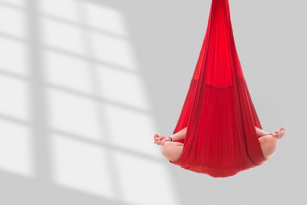 Photo fly yoga. a girl sits in a lotus position in a red hammock