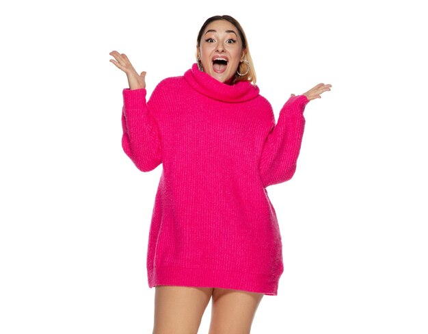 Flyer. Beautiful young woman bright pink comfortable sweater, long sleeve isolated on white studio background. Magazine style, fashion, beauty concept. Fashionable posing. Copyspace for ad.