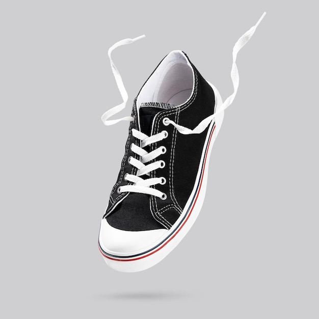 Flying black sneakers isolated on gray background Fashionable stylish sports casual shoes Creative minimalistic layout with footwear Mock up for your design Advertising for shoe store Copy space