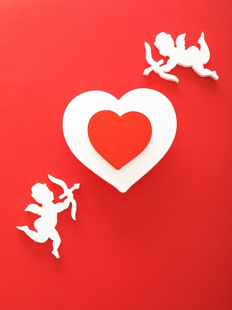 Flying cupid silhouette with hearts, gifts, happy Valentine's Day banners, paper art style. Amour on red paper