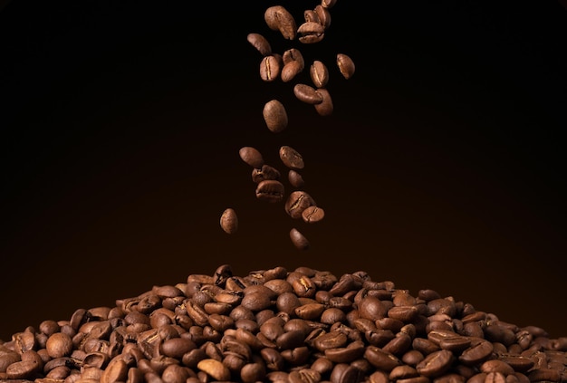 Photo flying down falling brown coffee beans on black background