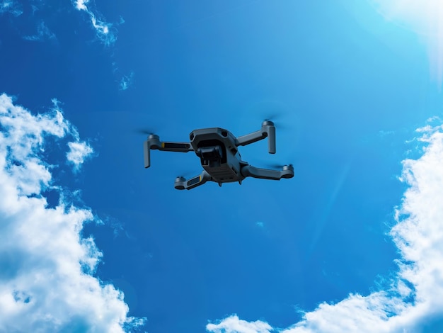 Flying drone against a blue sky with white clouds