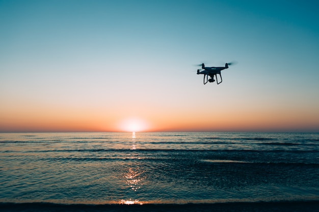 Flying drone on a background of sea sunset