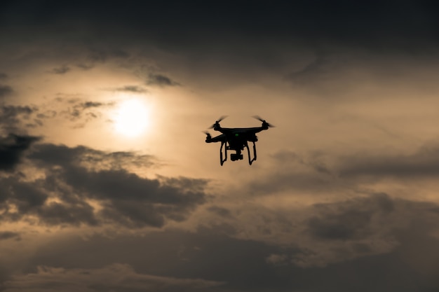 Photo flying drone with camera on the sky at sunset